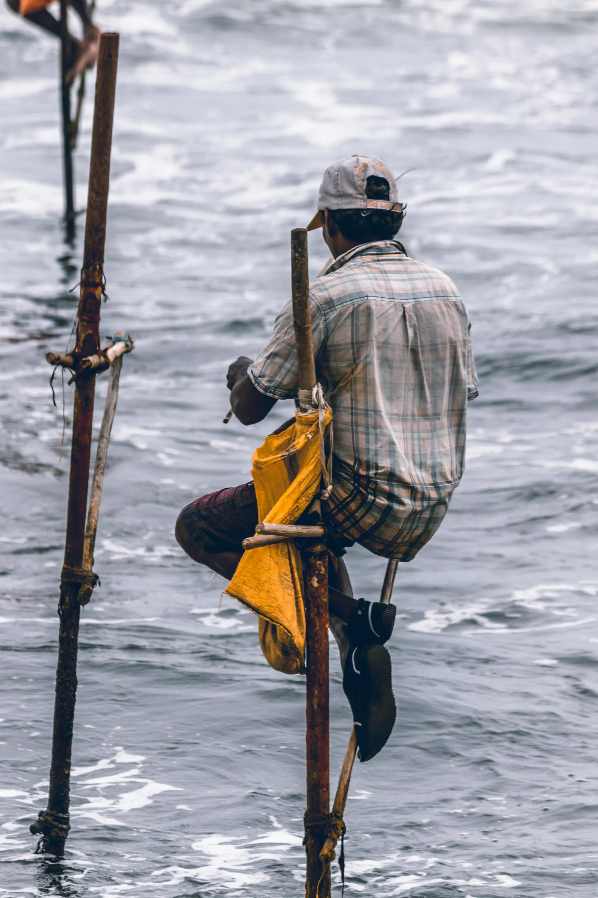Traditional Sri Lankan stilt fishermen perched above the ocean at sunrise