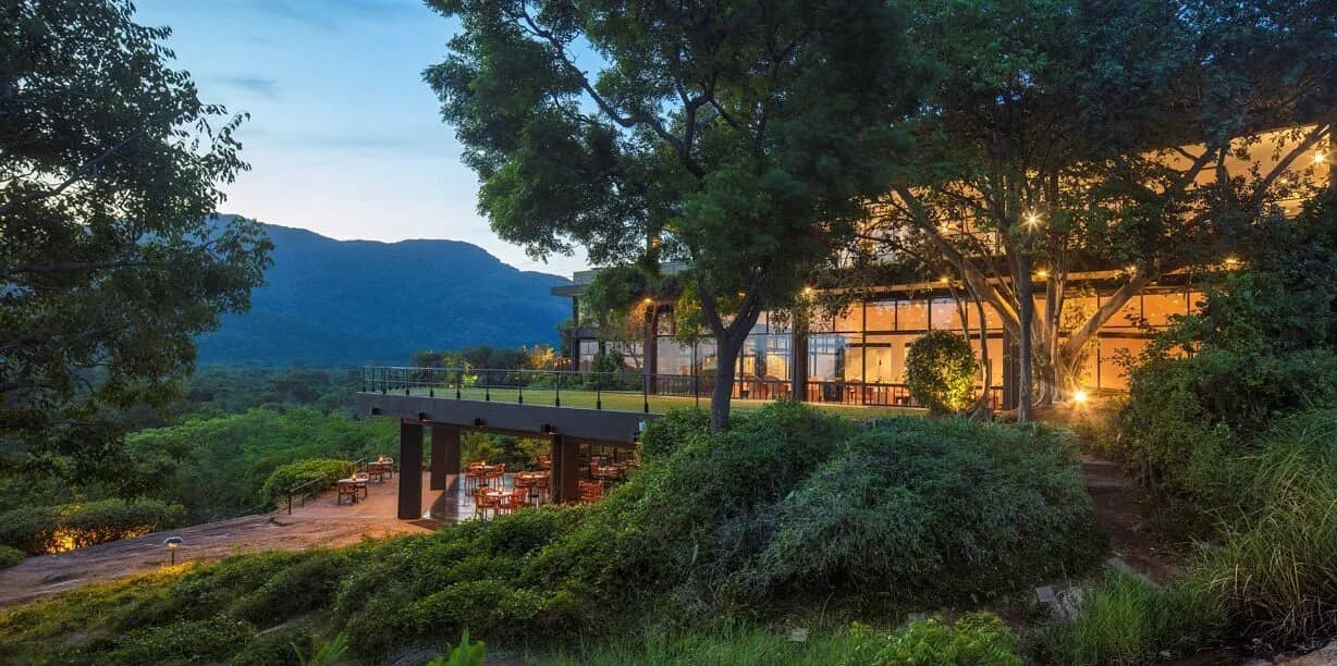 Sri Lankan landscape at sunrise with mist over lush green mountains and a luxury hotel