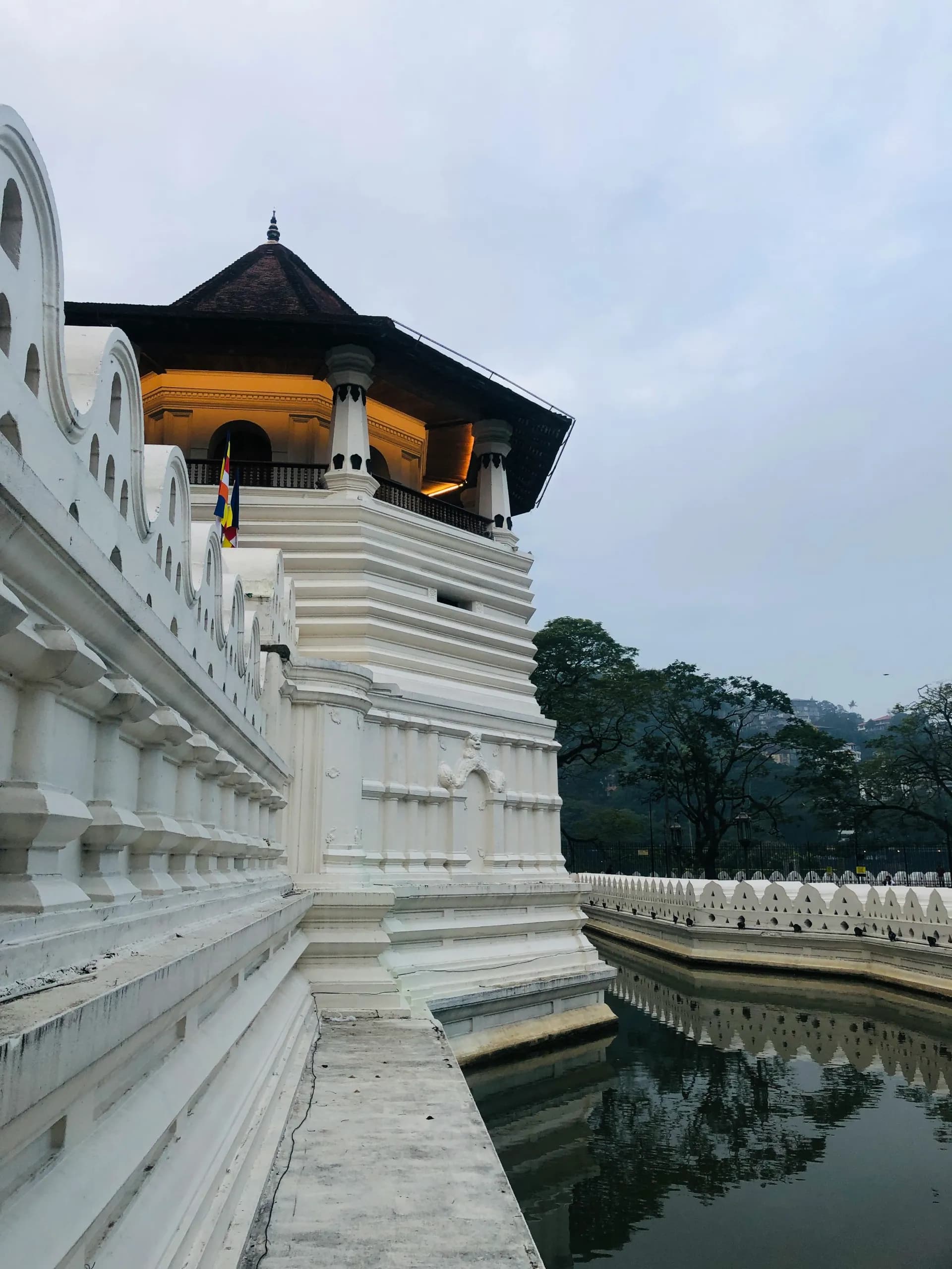 The sacred Temple of the Tooth Relic beside Kandy Lake at golden hour